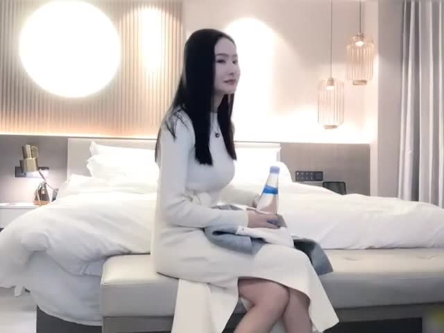 御姐范白裙美女坐在酒店床上�